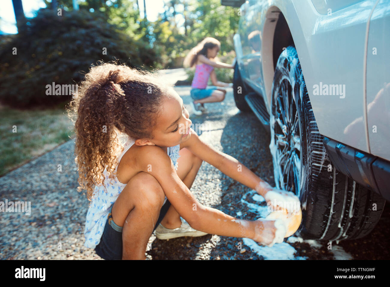 Mädchen waschen Auto in der Einfahrt Stockfoto