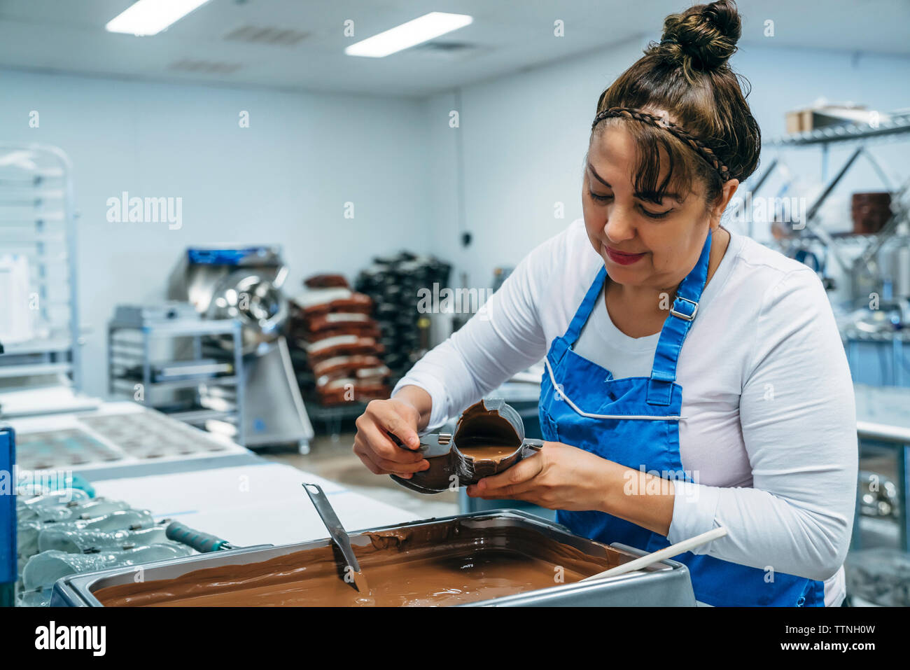 Weibliche baker Füllung Schokolade im Schuh geformte Behälter im Werk Stockfoto