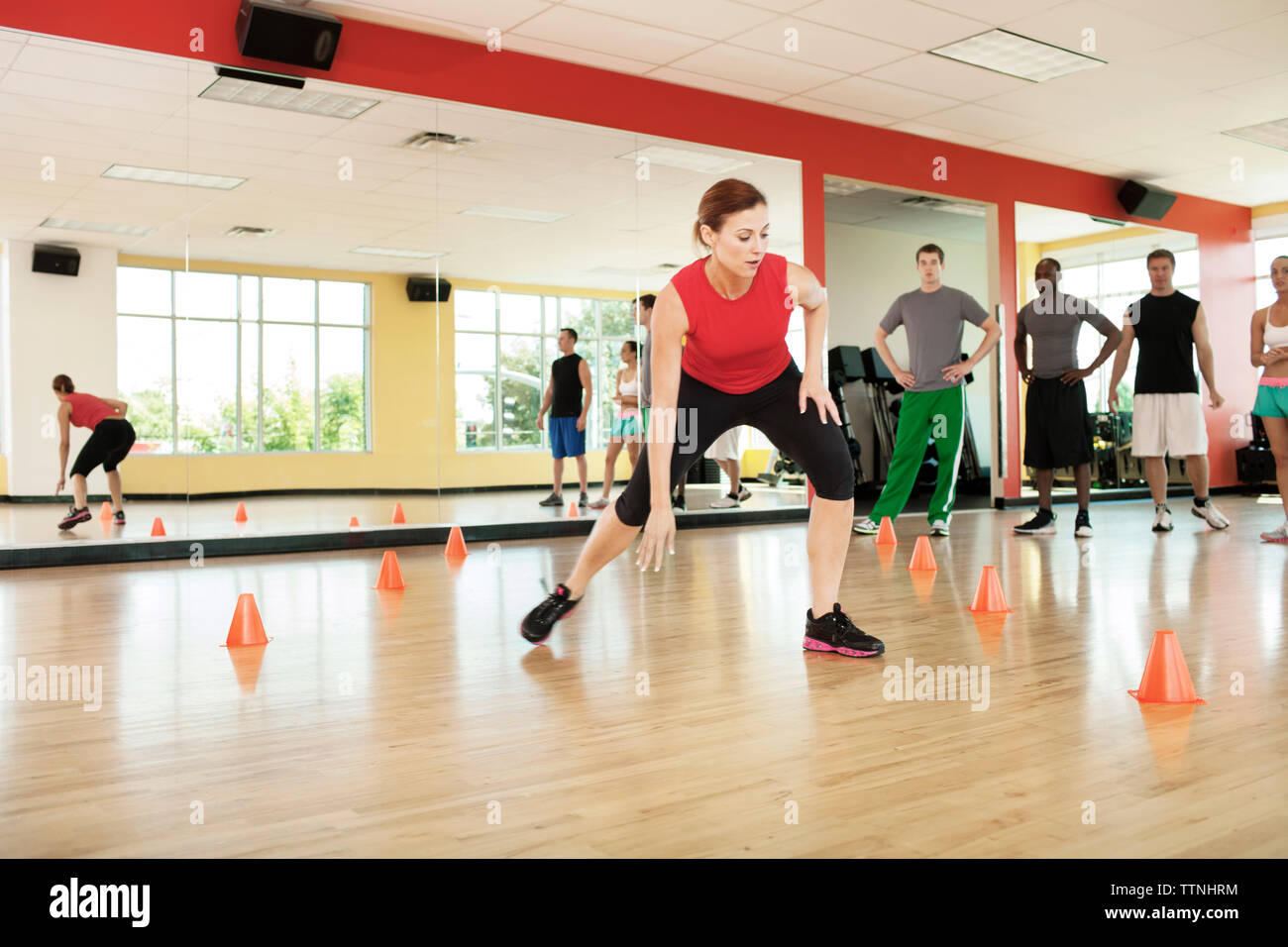 Kunden Fitness Instructor Training zwischen den Kegeln im Fitnessstudio suchen Stockfoto