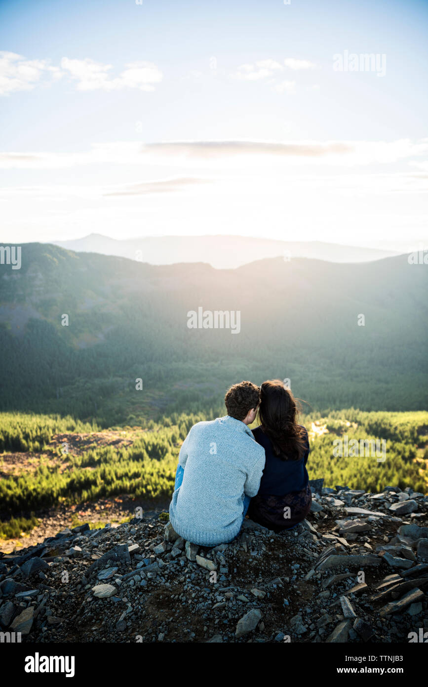 Ansicht der Rückseite des Paar sitzt auf Rock gegen Berge Stockfoto