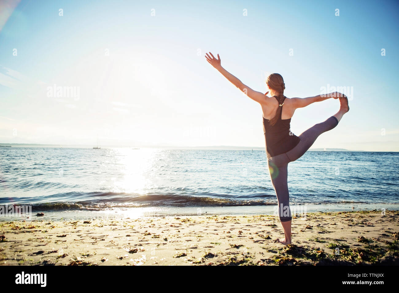 Ansicht der Rückseite Frau üben Hand große Zehe yoga Pose am Strand während der sonnigen Tag Stockfoto