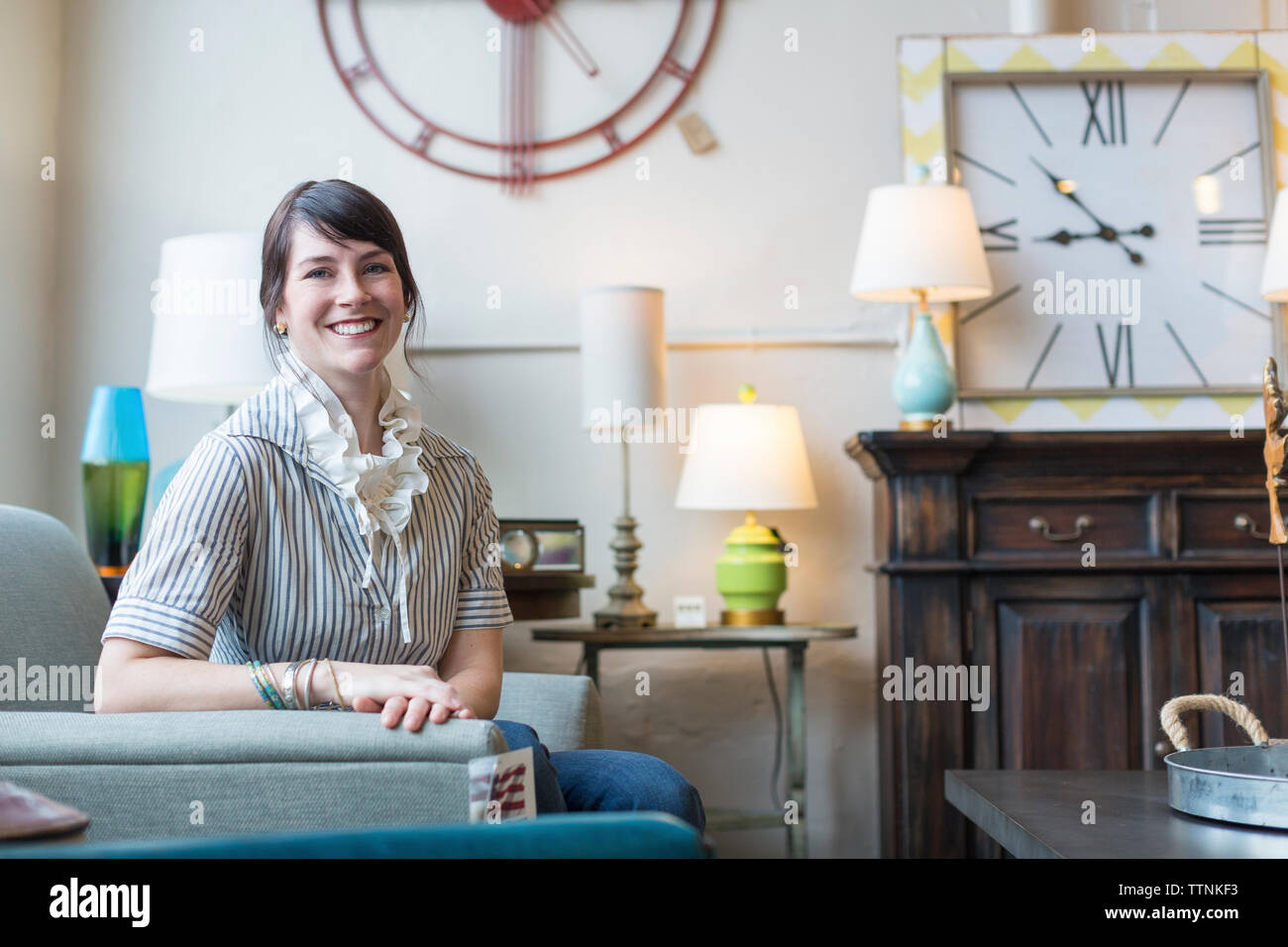 Portrait von lächelnden Eigentümer sitzt auf einem Sessel im Möbelhaus Stockfoto