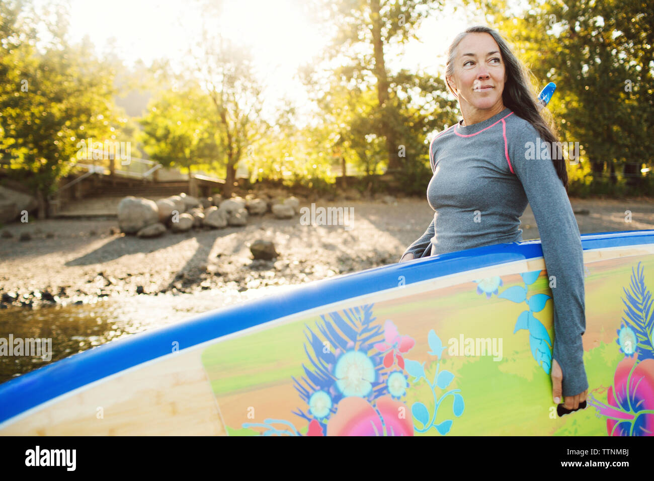 Frau weg suchen, beim Tragen paddleboard am Flussufer Stockfoto