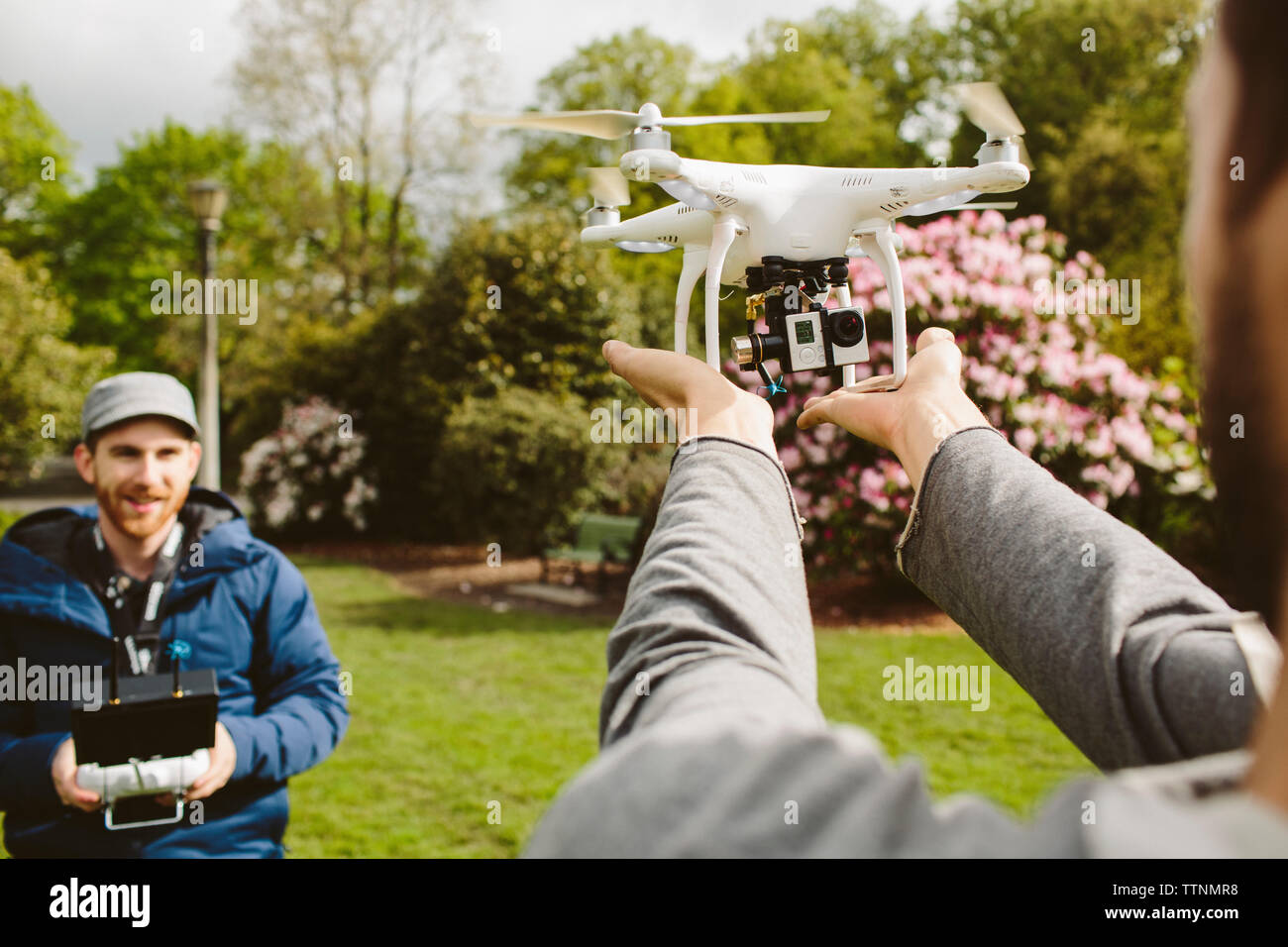 Mann Betrieb quadcopter, während, Sie halten es in Park Stockfoto