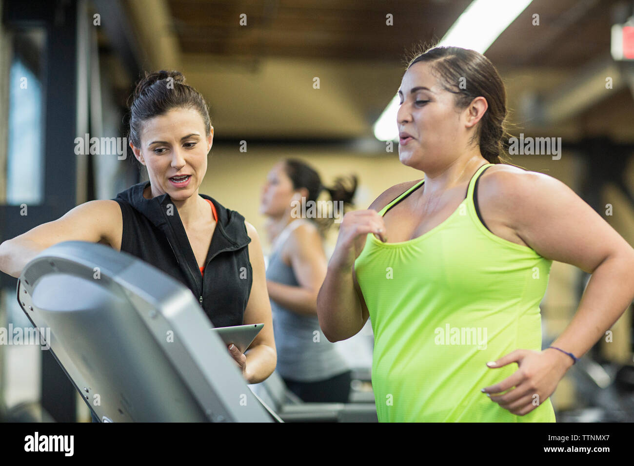 Trainer unterweisen Frau Ausübung auf Laufband im Fitnessstudio Stockfoto