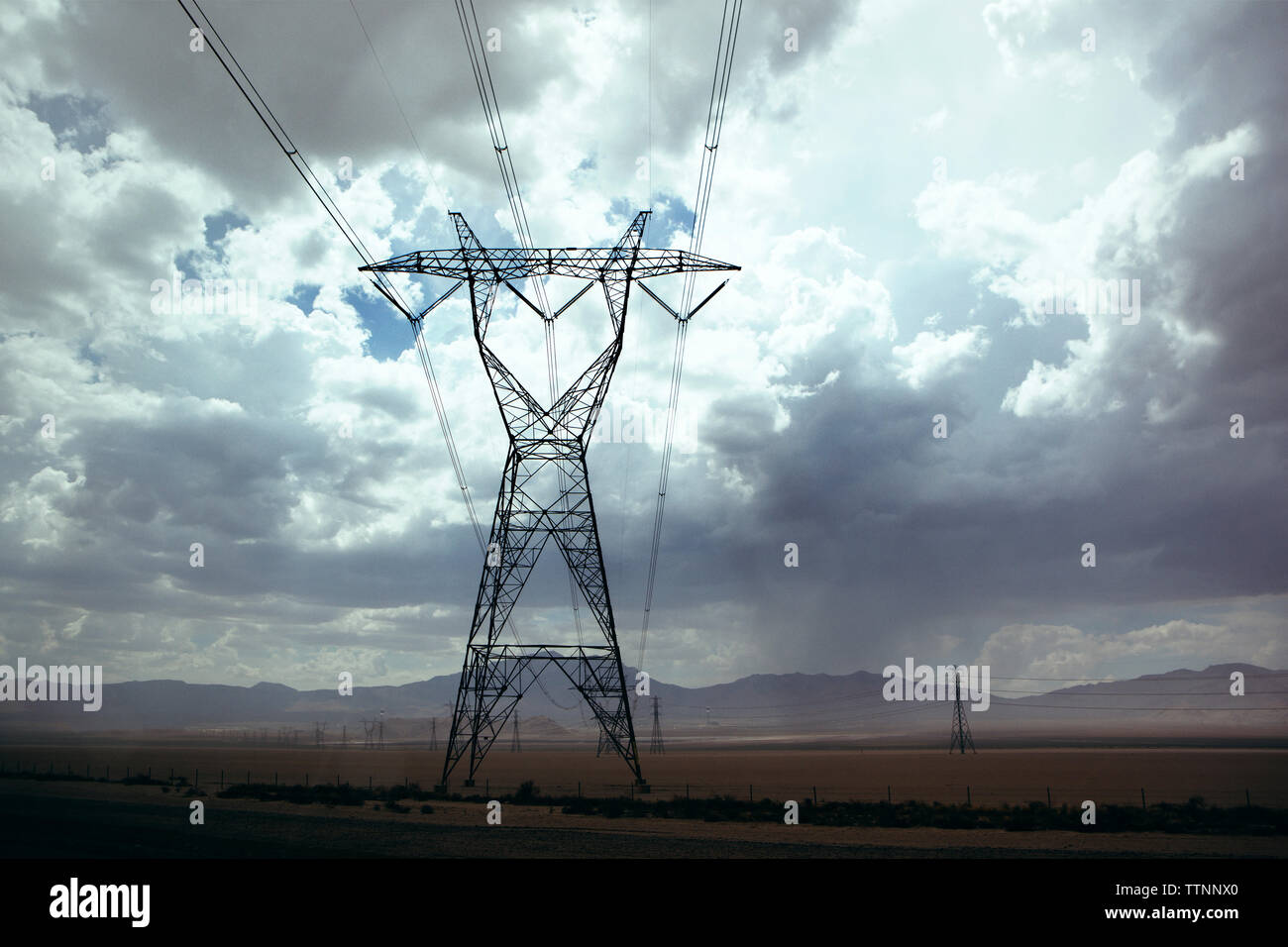 Strommasten auf Feld gegen bewölkter Himmel Stockfoto