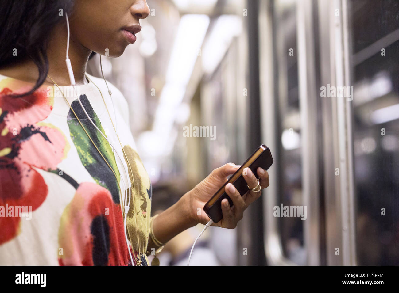 Frau Hören von Musik auf das Telefon während der Fahrt im Zug Stockfoto