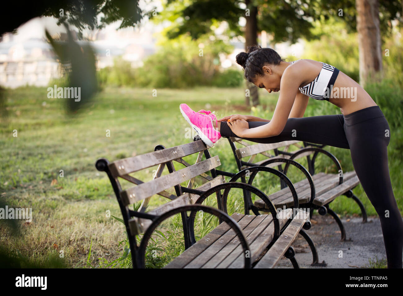 Sportliche Frau stretching Bein auf der Bank im Park Stockfoto