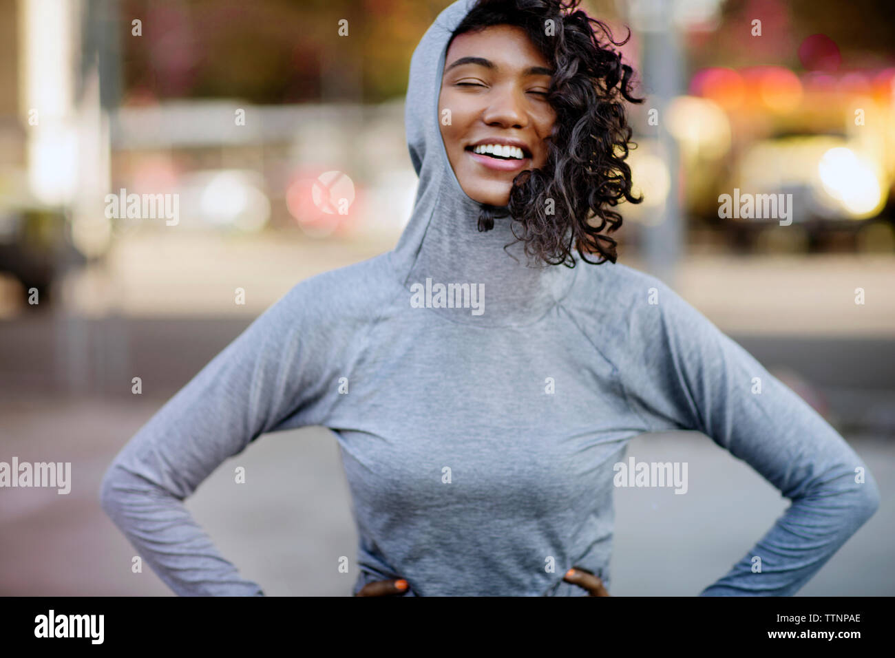 Lächelnde Frau mit Händen auf den Hüften stehen auf der Straße Stockfoto