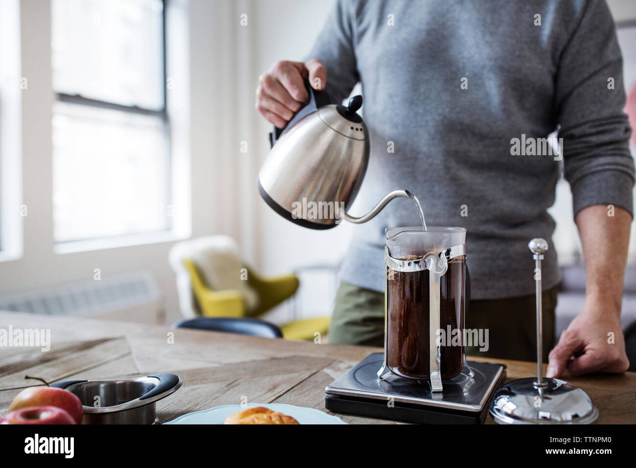 Mittelteil der Mann gießt Wasser in französischer Sprache drücken Sie während der Vorbereitung Kaffee zu Hause Stockfoto