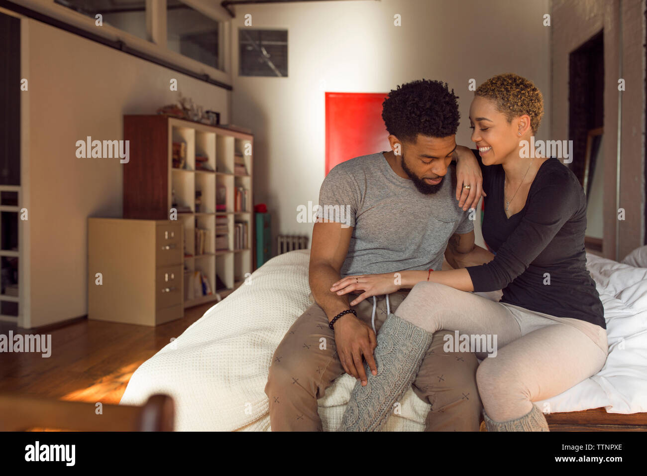 Glückliches junges Paar auf dem Bett zu Hause sitzen Stockfoto