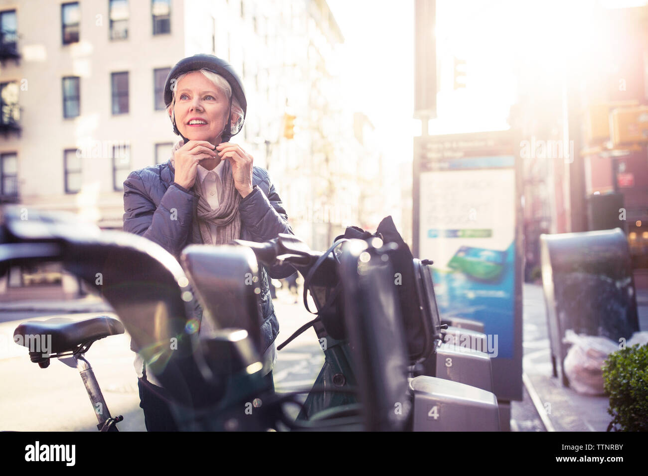 Nachdenklich senior Frau tragen Helm beim Stehen durch Fahrräder Stockfoto