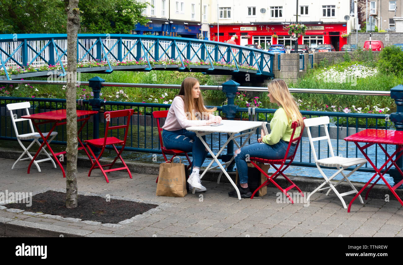 Freundinnen treffen sich zu einem Mittagessen im Freien in der Nähe des Flusses Garavogue footbridge​ in Sligo Town, Irland Stockfoto