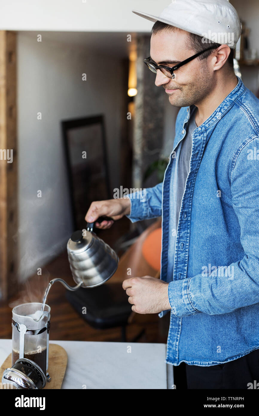Man gießt kochendes Wasser in Kaffee zu Hause Stockfoto