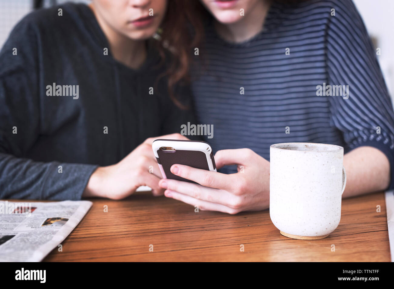 Mittelteil von Lesben mit Handy, während zu Hause sitzen Stockfoto