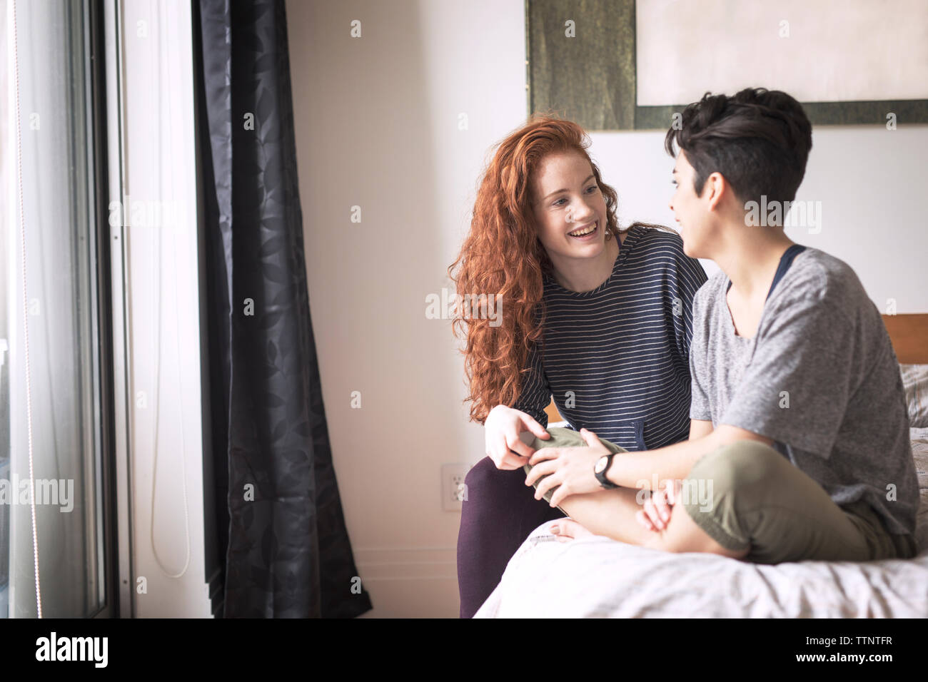 Glückliches Paar sprechen beim Sitzen auf dem Bett zu Hause. Stockfoto