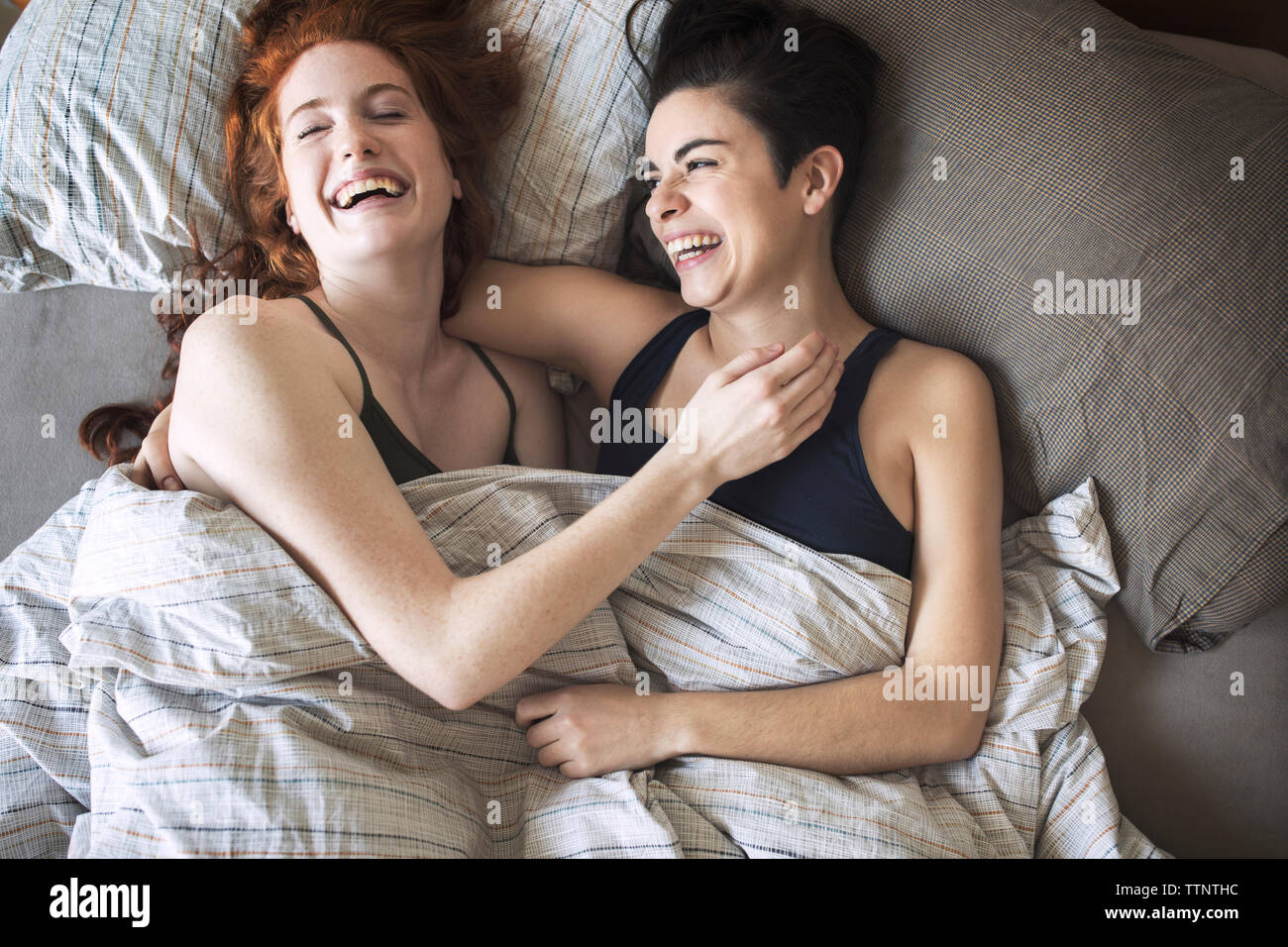 Hohe Betrachtungswinkel und fröhliche Lesben entspannen auf Bett Stockfoto