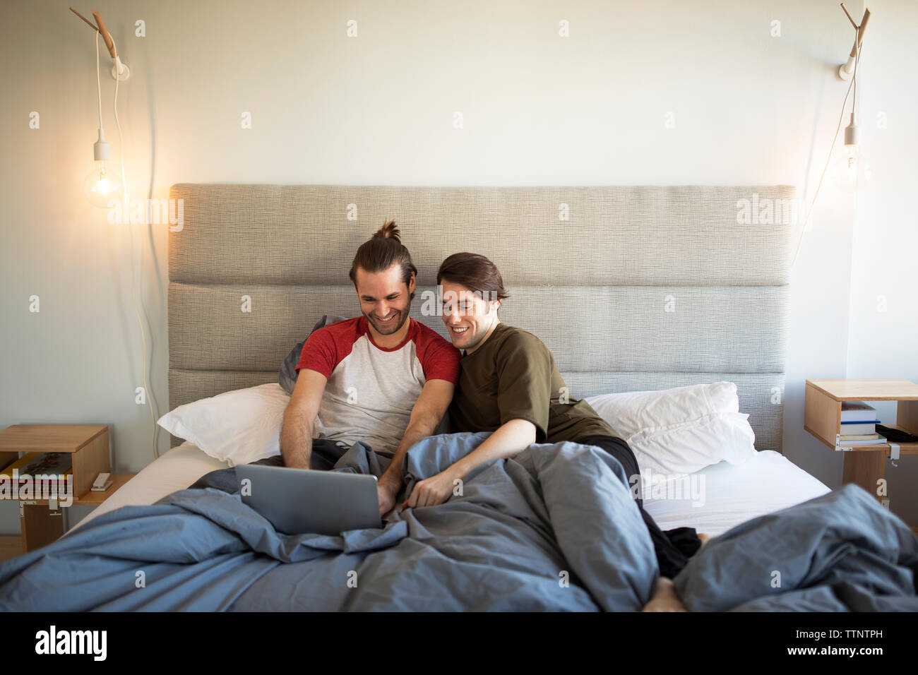 Homosexuelle Paare mit Laptop Computer, während Sie sich auf dem Bett zu Hause. Stockfoto
