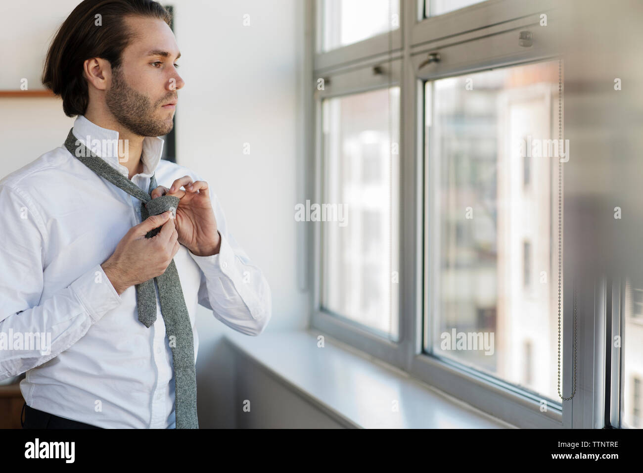 Nachdenkliche Menschen, durch Fenster Krawatte binden zu Hause suchen Stockfoto