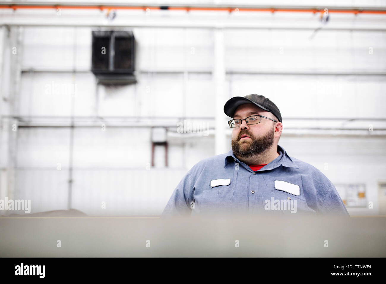 Arbeiter, der wegblickt, während er in der Stahlfabrik steht Stockfoto