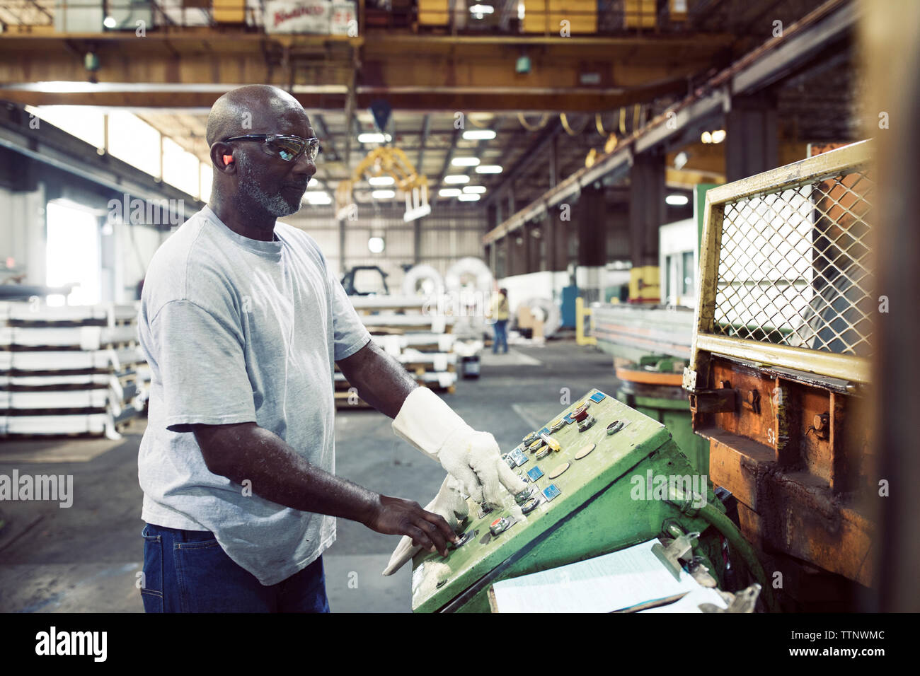 Seitenansicht der Arbeiter über die Maschine, während in der Stahlindustrie arbeiten Stockfoto