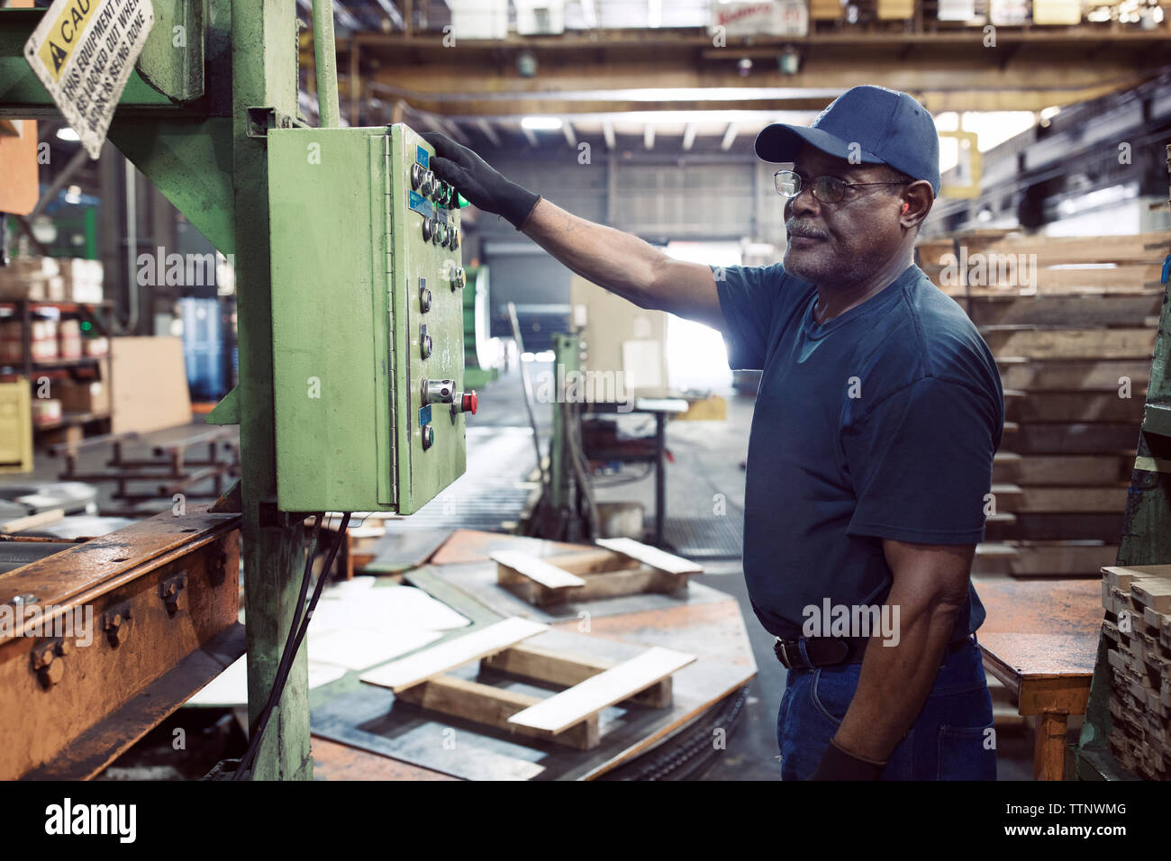 Seitenansicht des Arbeitnehmers mit Maschine, während in der Stahlindustrie arbeiten Stockfoto