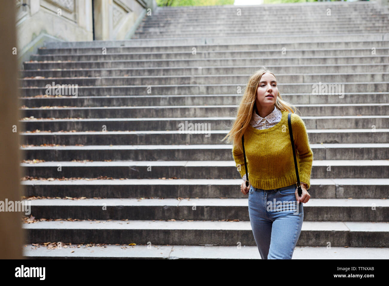 Junge Frau zu Fuß gegen Schritte im Park Stockfoto