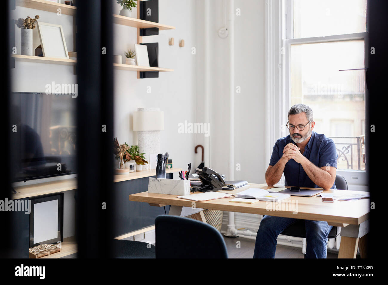 Nachdenklich Geschäftsmann am Schreibtisch in Creative office durch das Fenster gesehen sitzen Stockfoto