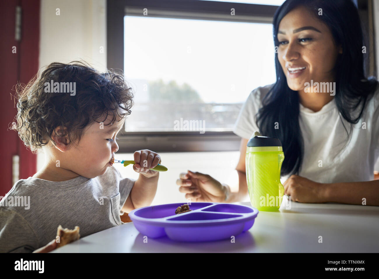 Lächelnde Mutter und Sohn essen zu Hause suchen Stockfoto