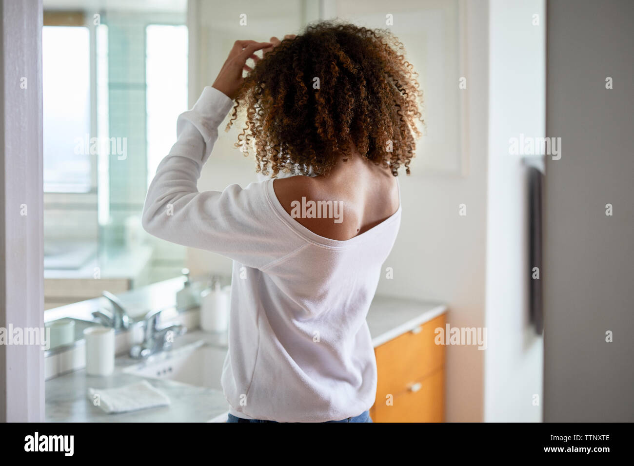Seitenansicht der Frau im Spiegel während zu Hause stehend Stockfoto