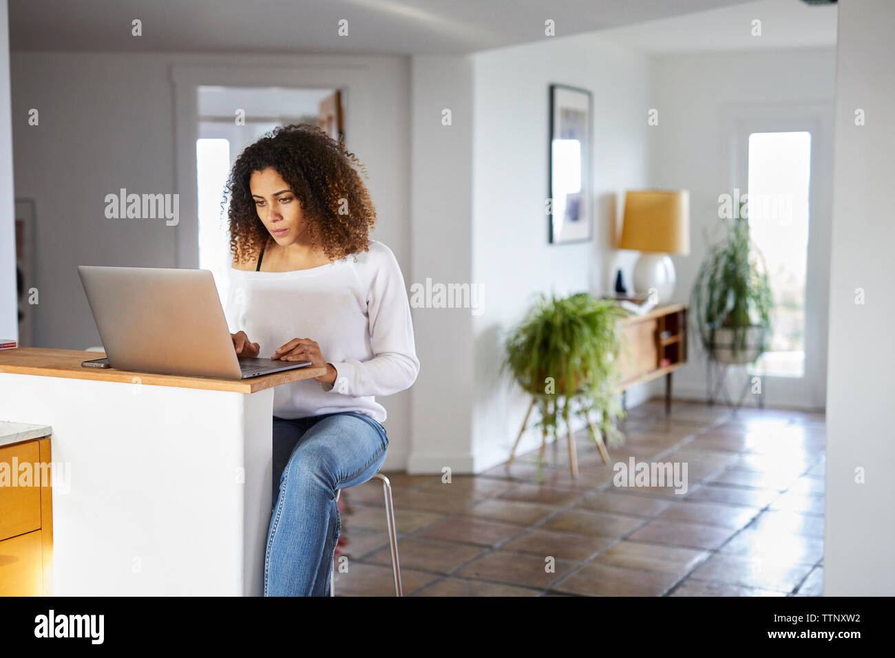 Frau mit Laptop auf dem Tisch zu Hause Stockfoto