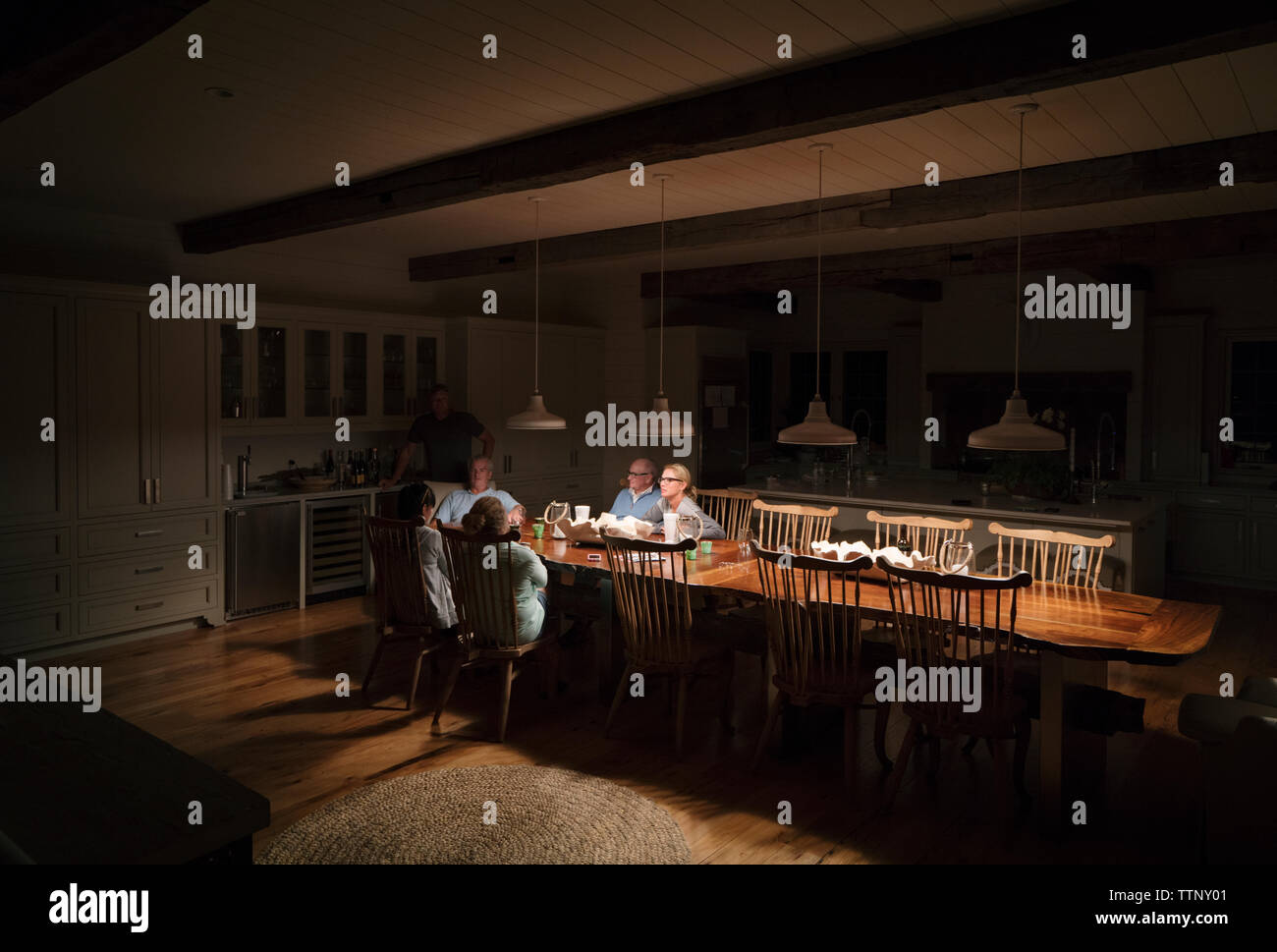 Familie sitzt am Esstisch beleuchtet Stockfoto