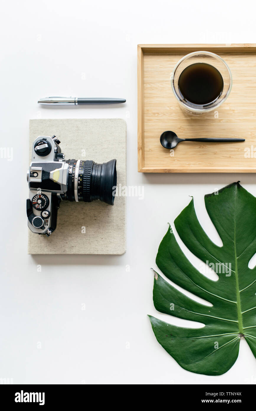 Ansicht von oben Kaffee in Holz- fach mit Kamera und Bürobedarf von monstera Blatt auf weißem Hintergrund angeordnet Stockfoto