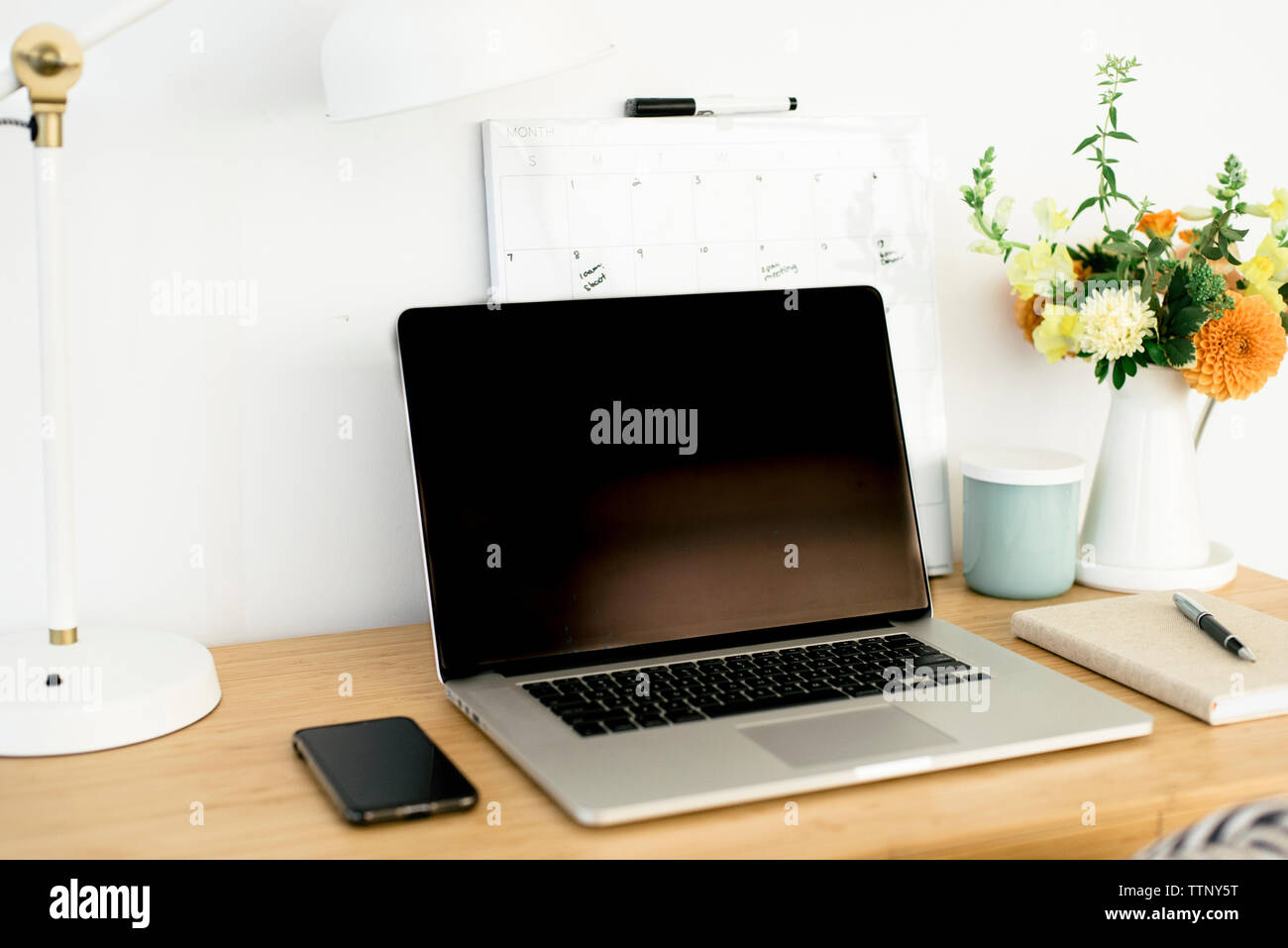 Hohe Betrachtungswinkel von Technologien mit Kalender- und Tischlampe von blumenvase auf hölzernen Tisch in Office Stockfoto