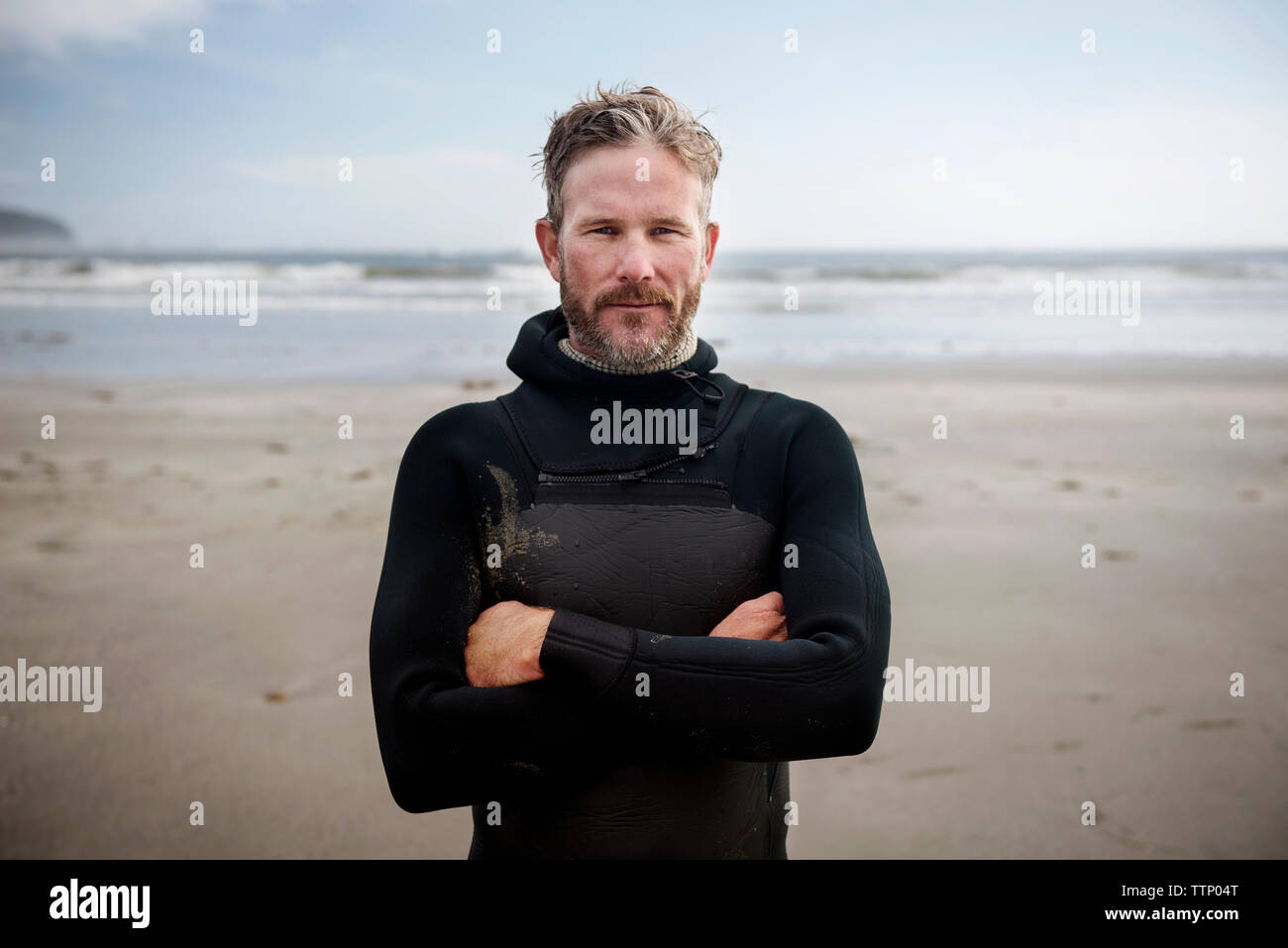 Portrait von Reifen surfer stehen mit den Armen am Strand gekreuzt Stockfoto