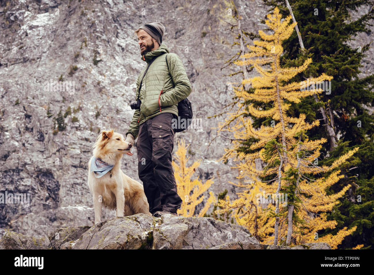 Low Angle View der Mann mit Hund steht auf Rock Formation im Winter Stockfoto