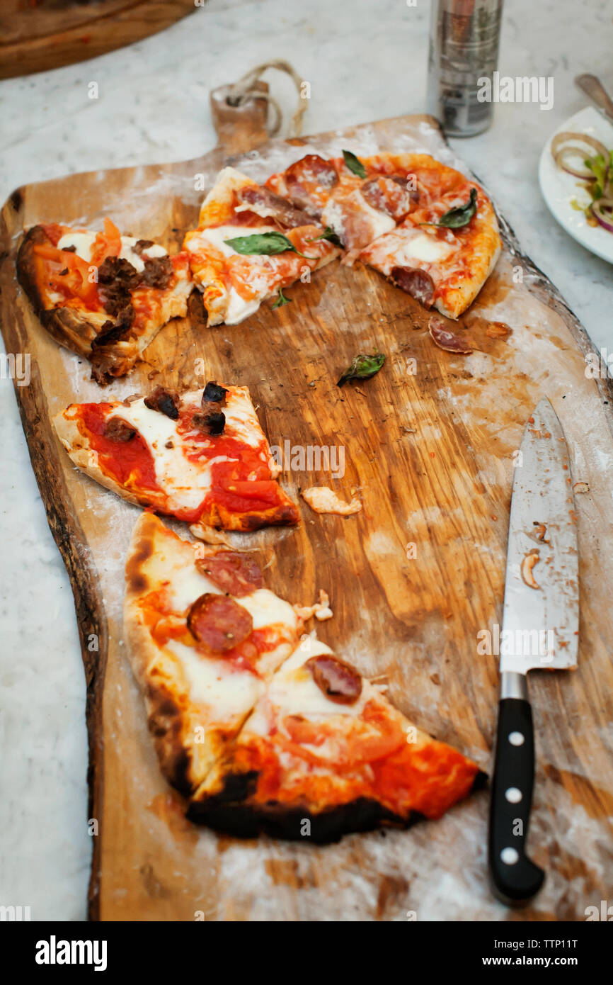 Hohe Betrachtungswinkel von Pizza Scheiben und Messer auf Schneidebrett Stockfoto