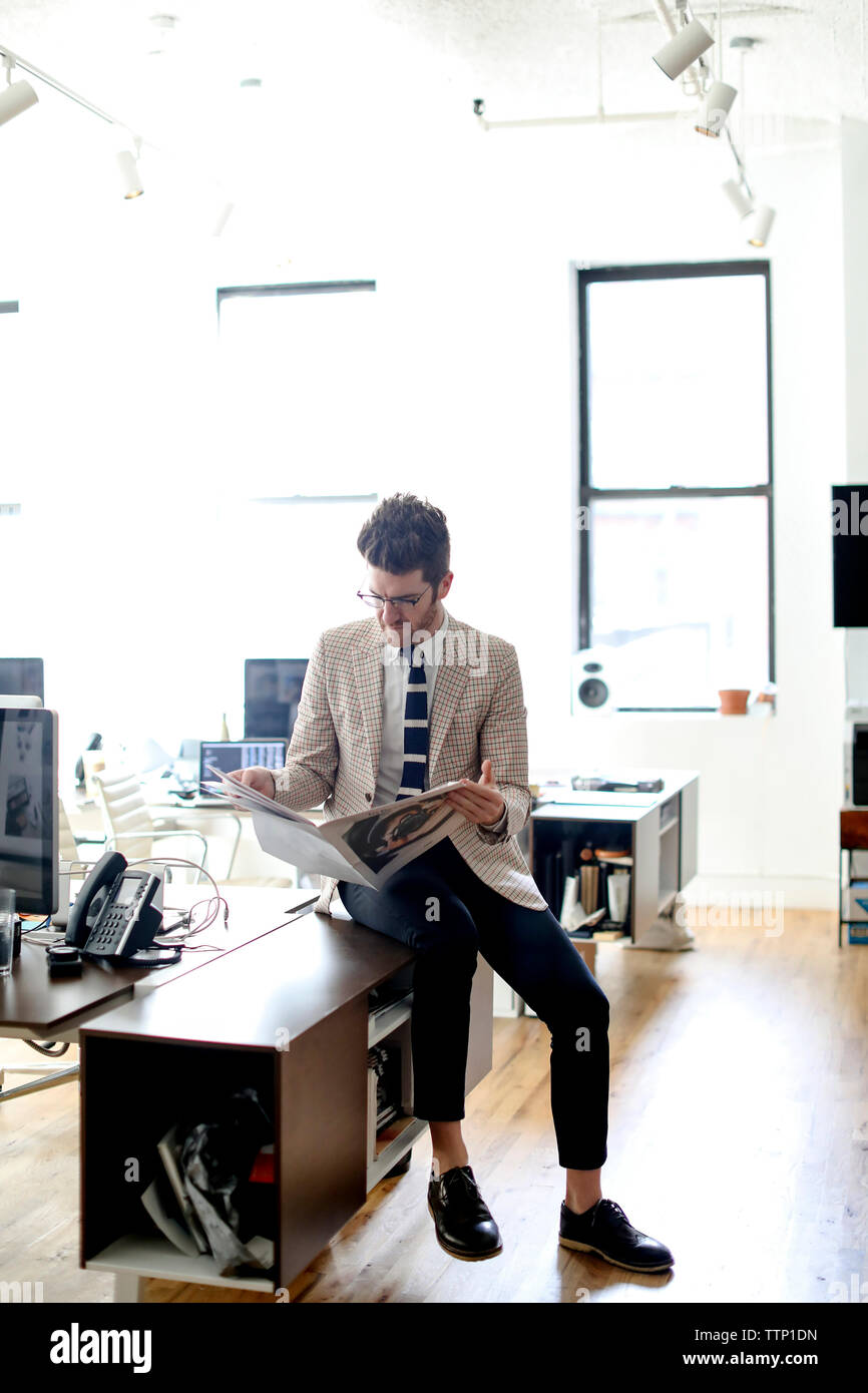 Volle Länge des Geschäftsmannes lesen Zeitung, beim Sitzen am Schreibtisch im Büro Stockfoto