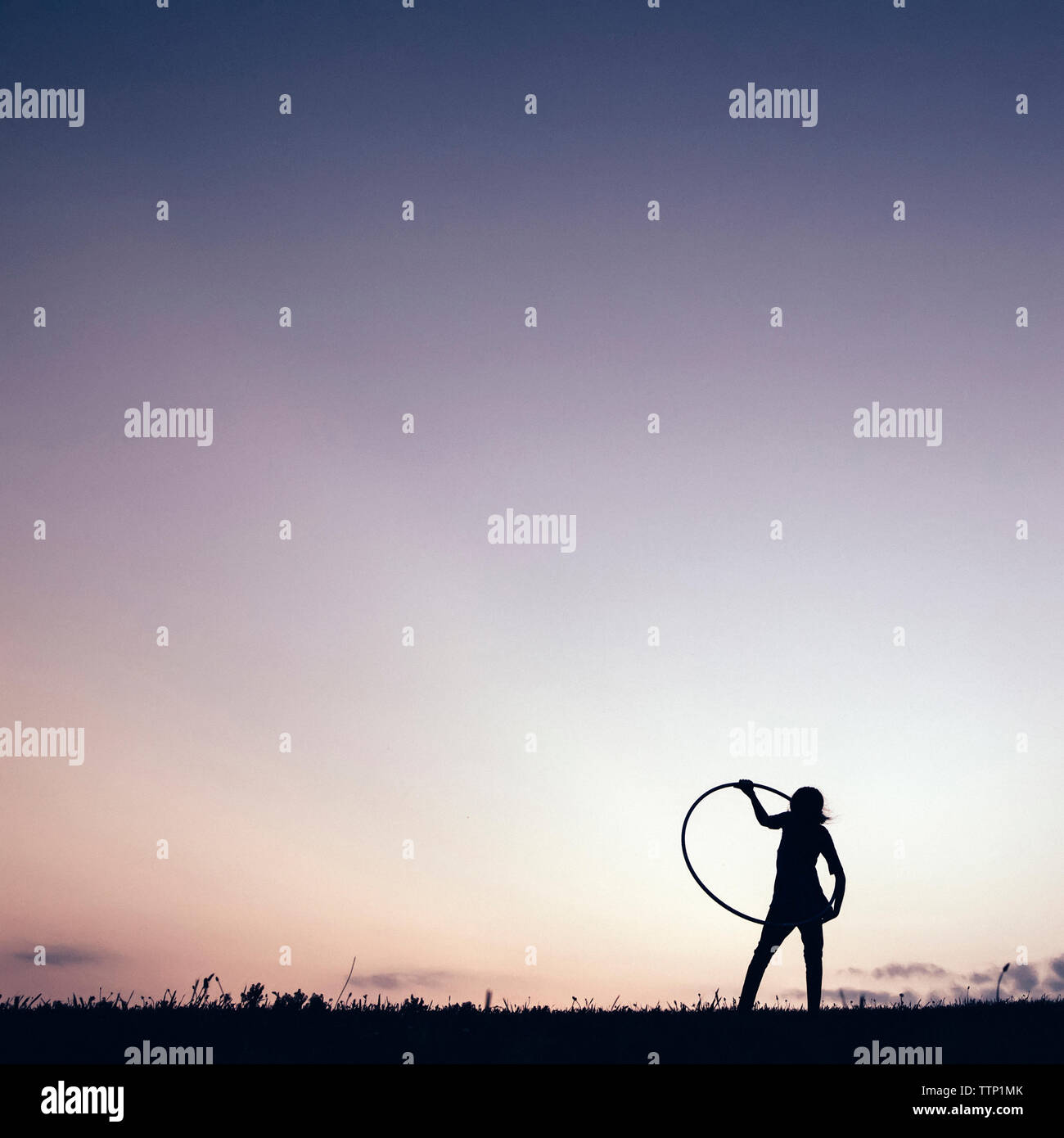 Silhouette Mädchen spielen mit Hula Hoop gegen den klaren Himmel Stockfoto