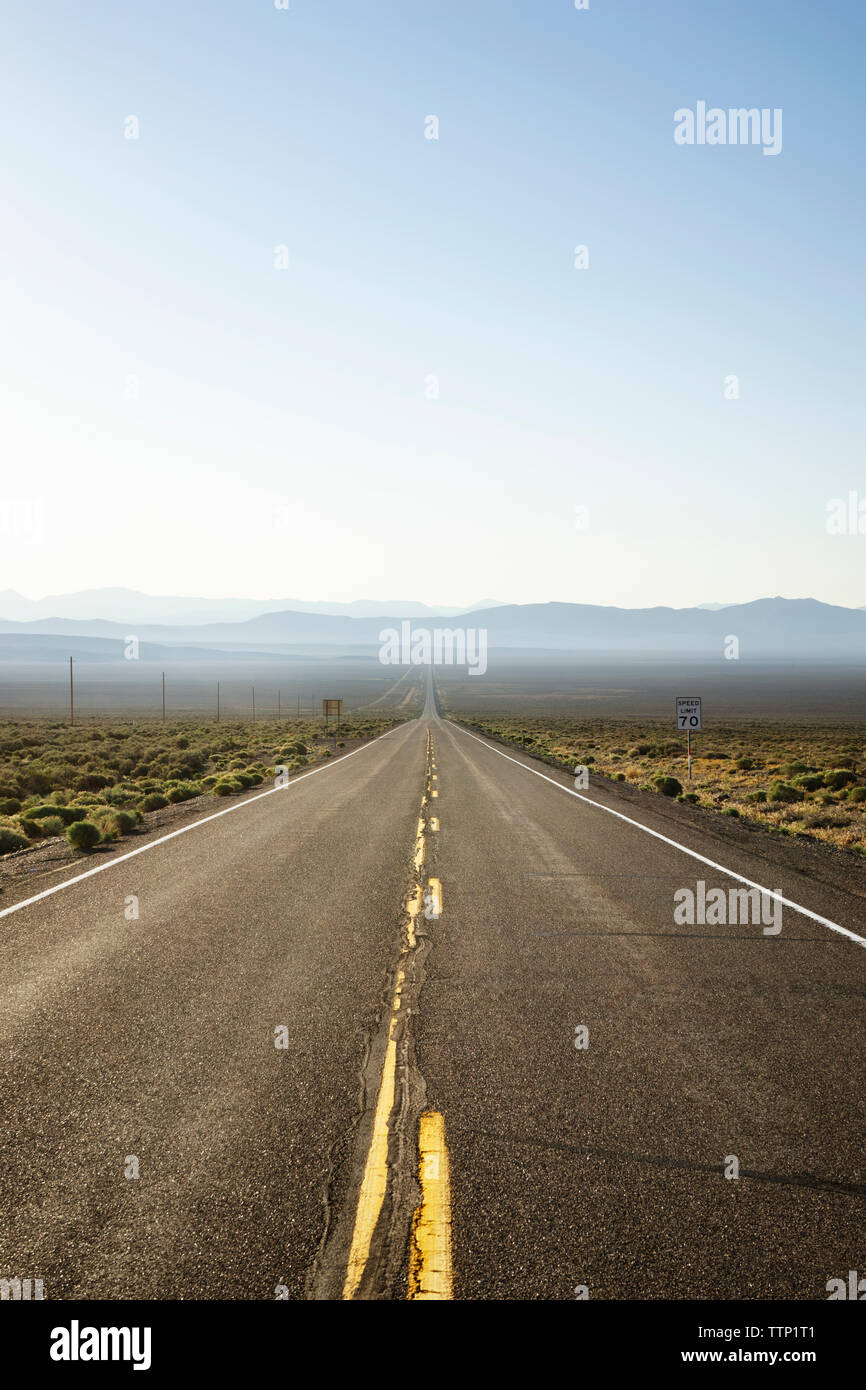 Country Road inmitten von Feld gegen blauen Himmel Stockfoto