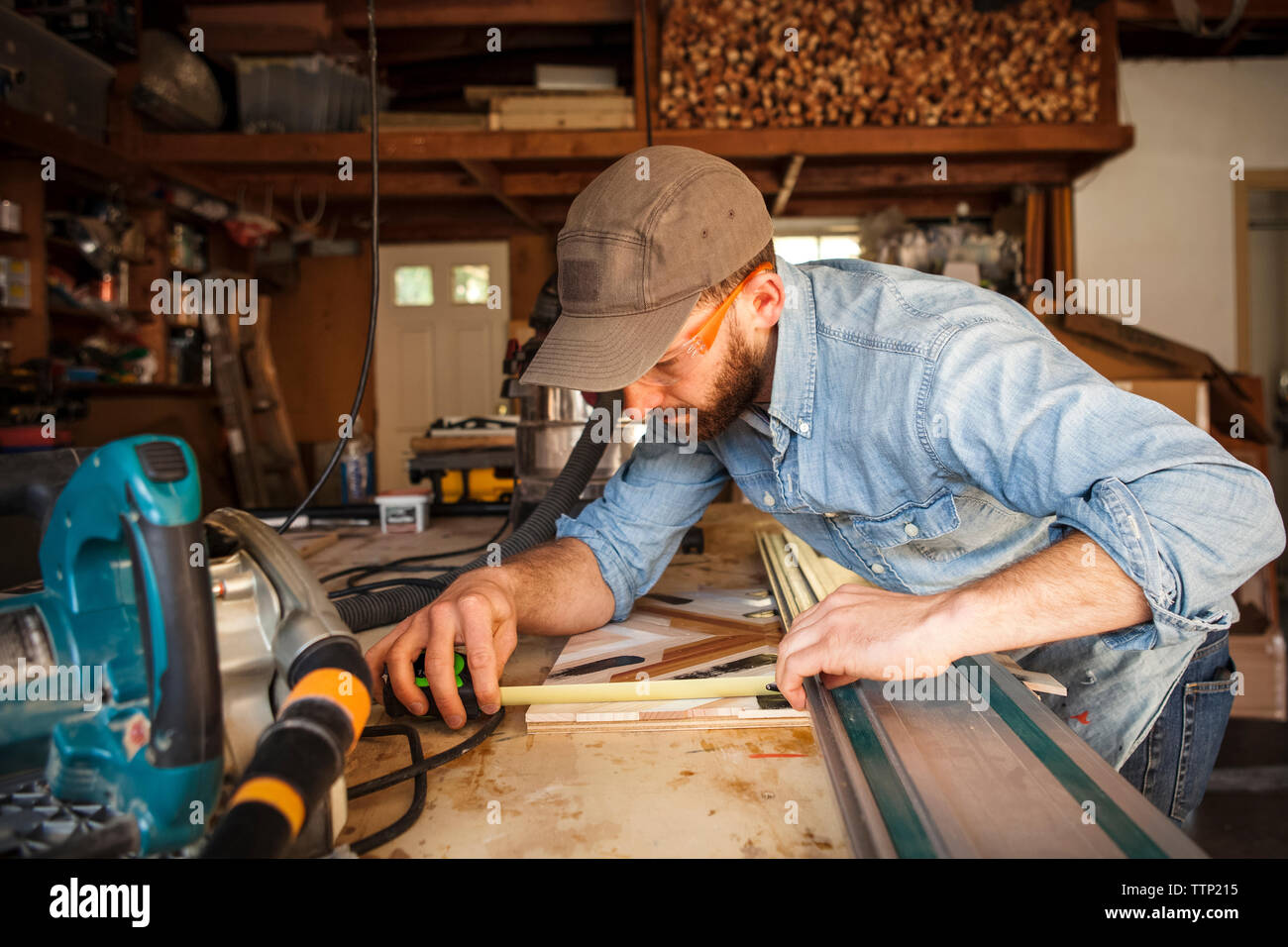 Ernsthafte Handwerker Messung von Holz in der Werkstatt Stockfoto