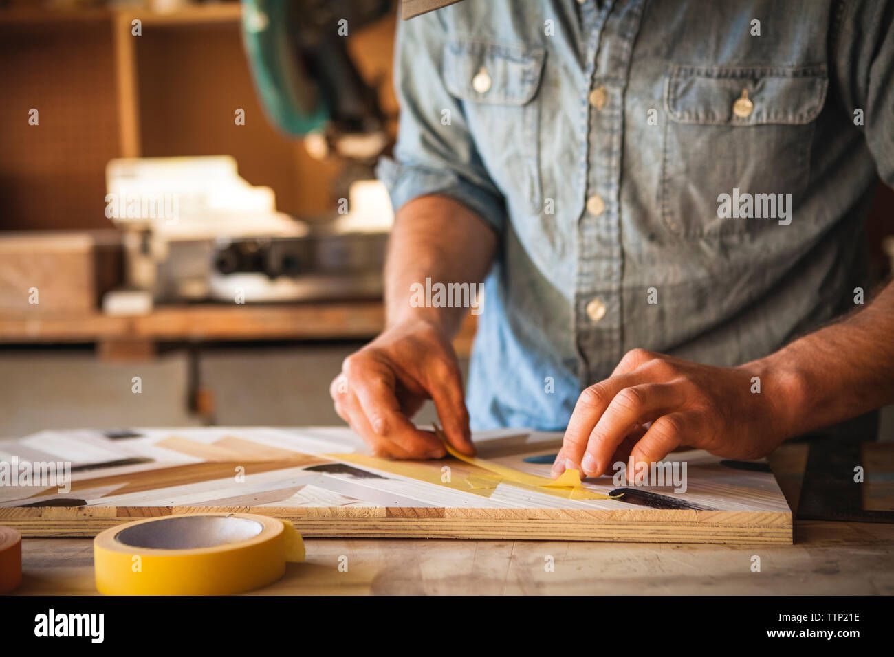 Mittelteil des Künstlers mit Klebeband auf Holz Kunst in Werkstatt Stockfoto