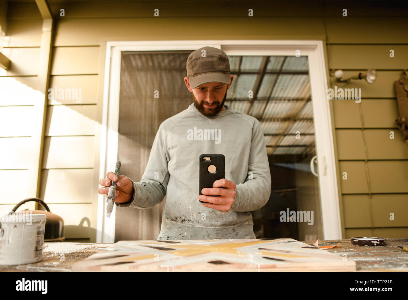 Zuversichtlich Künstler fotografieren Holz Kunst durch Mobiltelefon in Workbench Stockfoto
