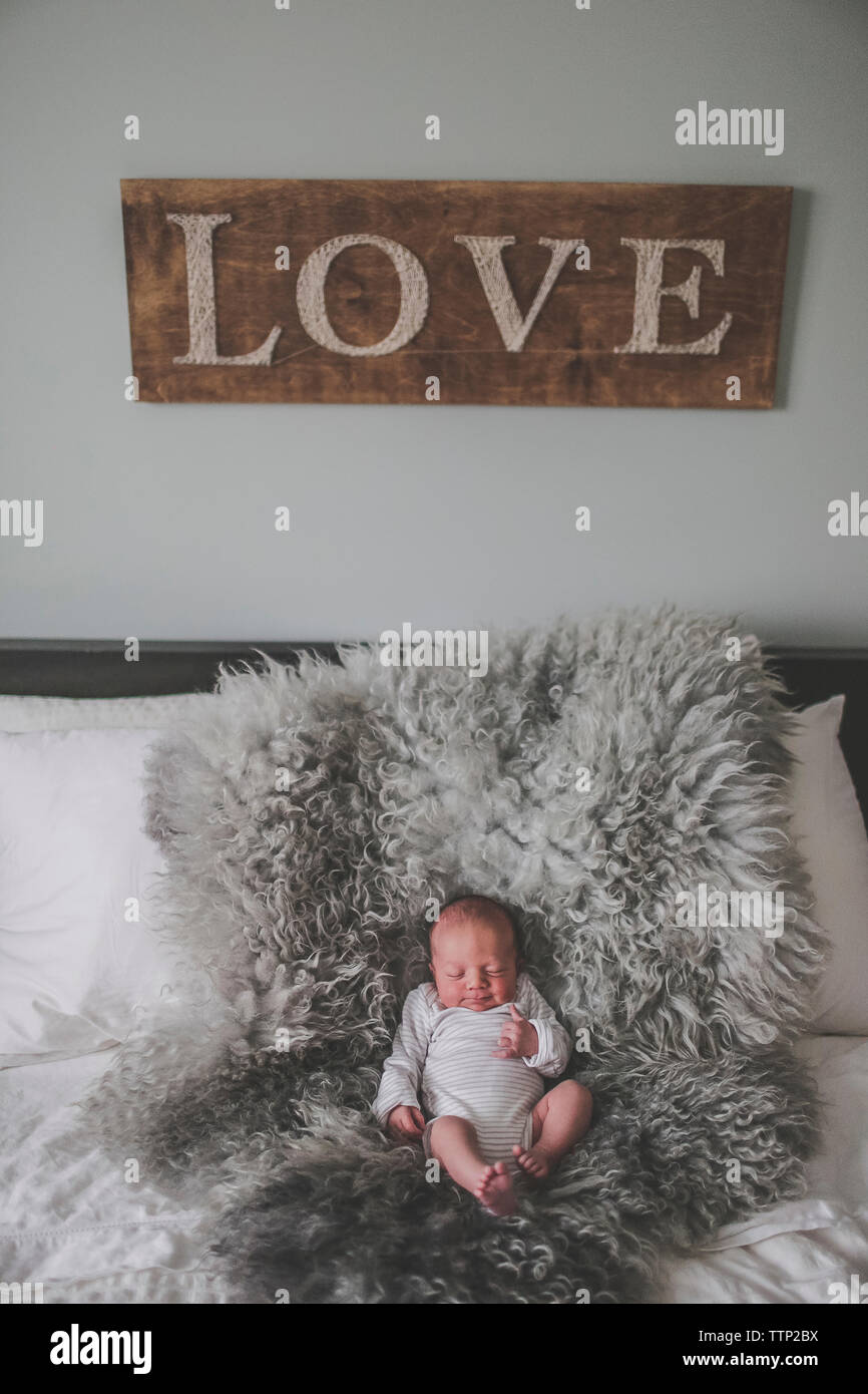 Hohe Betrachtungswinkel von baby boy Schlafen auf Fell Teppich im Schlafzimmer mit Liebe eingerichtet und an der Wand Stockfoto