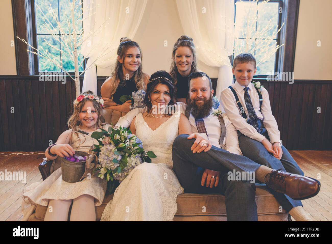 Portrait von jungvermählte Paar von Pageboy und Blumenmädchen mit brautjungfern auf Sofa während der Trauung Stockfoto