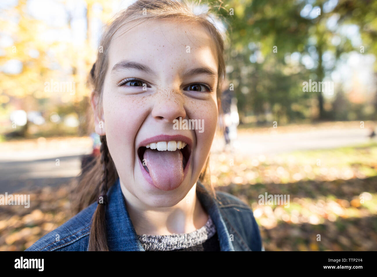 Close-up Portrait von Mädchen heraus haften Zunge, während in der PARK-Stellung Stockfoto