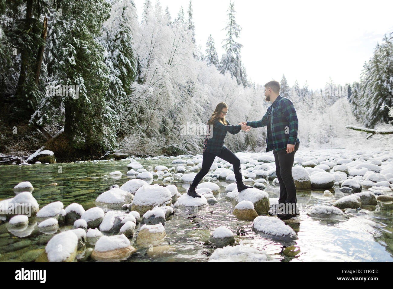 Mann, Frau, Überfahrt verschneite Felsen über Stream am Lynn Canyon Park Stockfoto