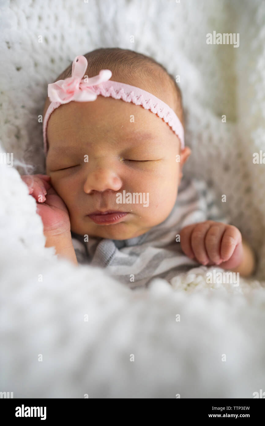 Close-up von niedlichen neugeborenen Mädchen mit Stirnband schlafen auf Bett zu Hause Stockfoto