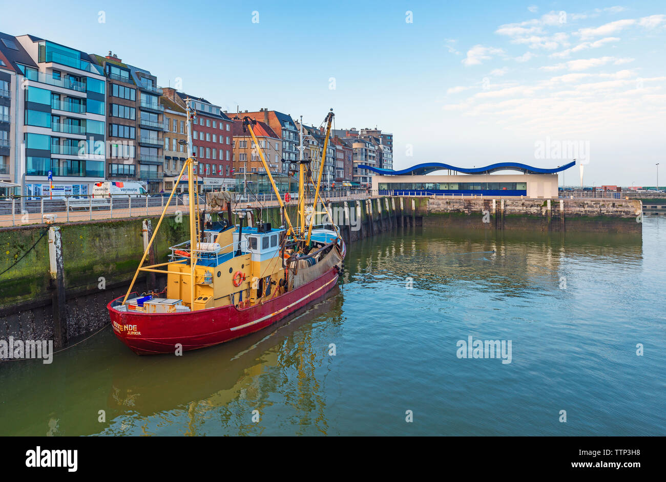 Fischerboot im Hafen von Oostende Stadt an der Uferpromenade mit dem modernen Fischmarkt im Hintergrund, Westflandern, Belgien. Stockfoto