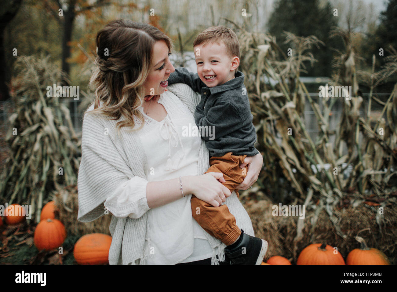 Fröhliche Mutter mit niedlichen Sohn auf Pumpkin Patch im Herbst Stockfoto